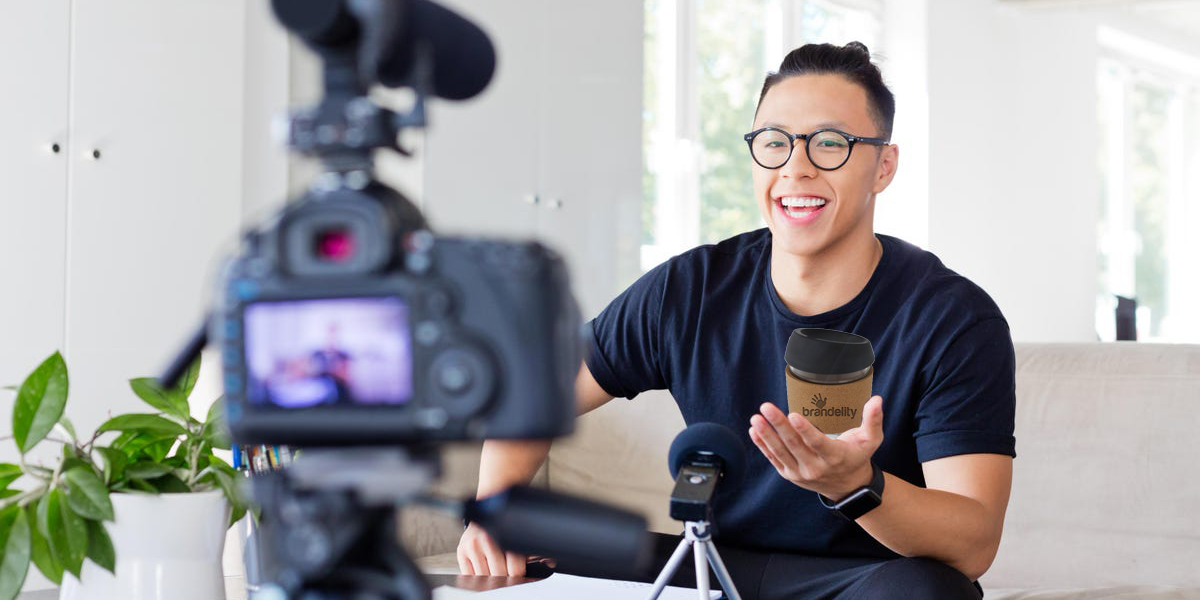 Influencer In Front Of A Camera Holding A Branded Coffee Cup